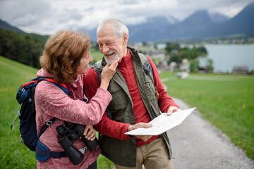 Active elderly couple hiking together in mountains, enjoying nature. Senior tourists looking at route on map.