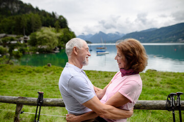 Portrait of elderly couple in love hiking together in mountains. Senior tourists embracing, going to kiss.