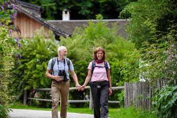 Active elderly couple on trip together, during spring day. Senior tourists visiting, exploring new places. Sightseeing, holding hands.