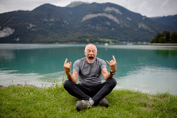 Active senior man is thrilled to accomplish challenging hiking trail. Happy elderly man resting on...
