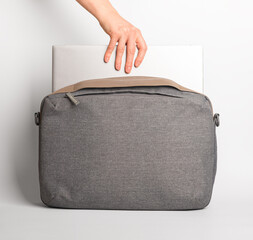 Hand putting laptop computer, notebook from bag