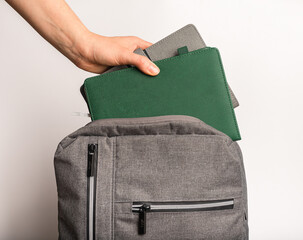 Hand putting books, planners, notebooks into backpack, schoolbag