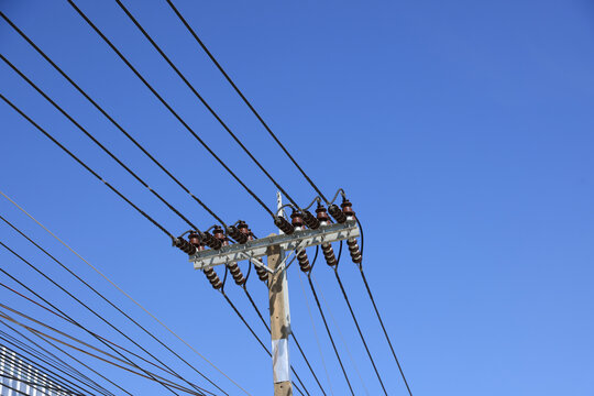 A striking image of a utility pole with power lines set against a vivid blue sky.