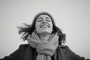Black and white portrait of a joyful young woman with flowing hair and a bright smile, conveying happiness and carefree emotion.