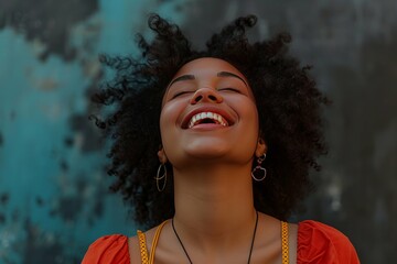 Joyful young woman with curly hair laughing against a textured blue background, depicting happiness and positivity.