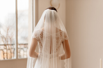 Mariée dans sa robe blanche portant son voile - 773387290