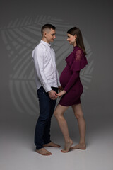 two people, portrait of a pregnant couple on a grey background, pregnant couple standing