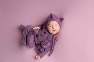 a little newly born child in a dragon costume. little dragon newborn photo shoot. sleeping child with a toy