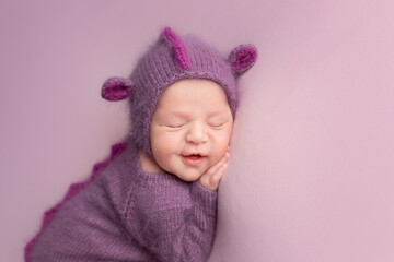 a little newly born child in a dragon costume. little dragon newborn photo shoot. sleepy grinning child