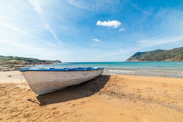 Small wooden boat on the sand under a blue sky