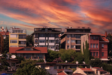 Evening view of the city. Sunset orange sky and beautiful landscape, houses and city streets,...