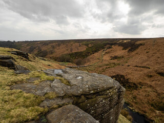 Fototapeta na wymiar Fields, hills, mountains and a large rock in the foreground. Yorkshire moors. Wild and bleak. Rocky hill top scenic view at dusk