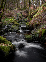 Mountain river in England, dreamy scenery, moss-covered stones and beautiful waterfall in the forest. Sunny creek in spring cloudy Yorkshire evening. small cascade surrounded by moss and autumn leaves