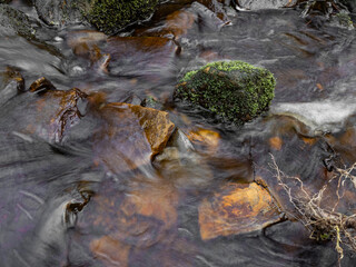 Mountain river in England, dreamy scenery, moss-covered stones and beautiful waterfall in the forest. Sunny creek in spring cloudy Yorkshire evening. small cascade surrounded by moss and autumn leaves