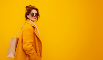 Happy woman with shopping bag in hands on yellow background