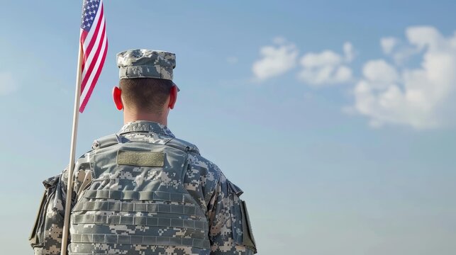 Soldier in camouflage uniform holding American flag against sky. Military service and patriotism concept.