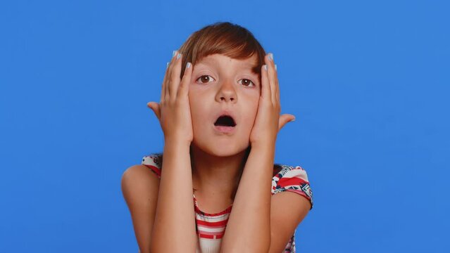 Oh my God, Wow. Young preteen child girl kid looking surprised at camera with big eyes, shocked by sudden victory game winning lottery goal achievemen good news. Children isolated on blue background