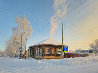 Rustic wooden house under the snow. Rural street.
