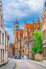 Obraz premium Brugge city historical centre, narrow cobblestone street with buildings and houses in Bruges old town Steenstraat quarter, St. Salvator's Cathedral church Romanesque style, Flemish Region, Belgium