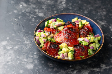 Lemon and tomato paste glazed Mediterranean style chicken thighs served with avocado and cucumber salsa, low carb keto meal concept