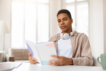 Young man reading a book with headphones