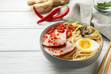 Delicious ramen in bowl on white wooden table, space for text. Noodle soup
