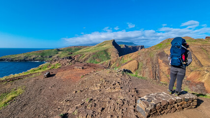 Fototapeta premium Father with baby carrier looking at majestic Atlantic Ocean coastline at Ponta de Sao Lourenco peninsula, Canical, Madeira island, Portugal, Europe. Coastal hiking trail along rocky rugged cliffs