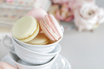 French macaroons in porcealin cup. Roses and love letters in the background.