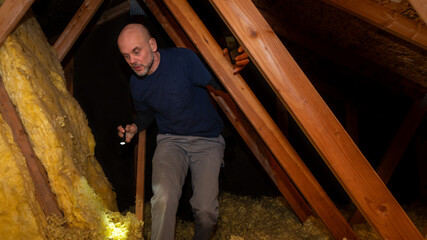 Home inspector inspecting condition of home attic and finding moisture on the ceiling.