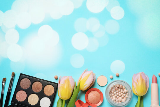 Different makeup products and beautiful tulip flowers on light blue background with space for text, flat lay. Bokeh effect