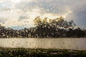 A lake landscape seen through a window with a defocused raindrops, in the afternoon in the eastern Andean mountains of central Colombia.