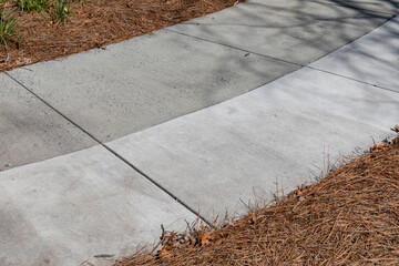 Sweeping concrete walkway with new section added flanked with pine straw, creative copy space, old...