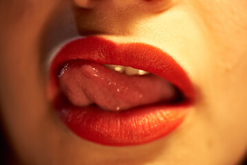 Female mouth with red lipstick. The girl sexually licks her lips in red lipstick with her tongue.