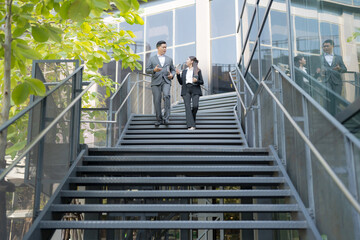 Business colleagues conversing on staircase - obrazy, fototapety, plakaty