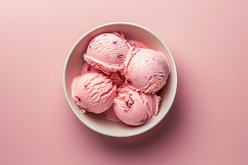 Top view of a bowl of strawberry ice cream balls with raspberries in pink background