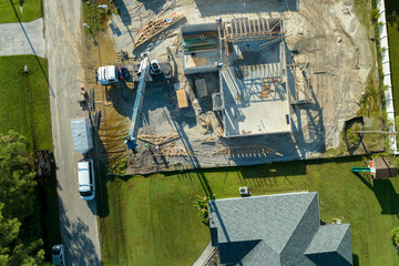 Professional builders and crane truck working on roof construction of unfinished suburban home with...