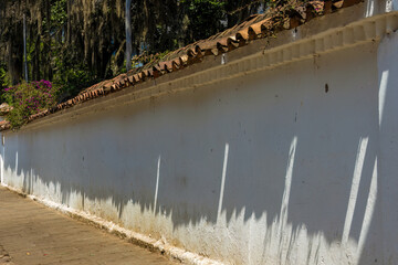 A long white, weathered old wall illuminated by the sun of the afternoon, in the colonial town of Villa de Leyva, in central Colombia.