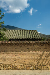 A gray old clay tile roof and an adobe wall against the blue sky, in the colonial town of Villa de Leyva in central Colombia.