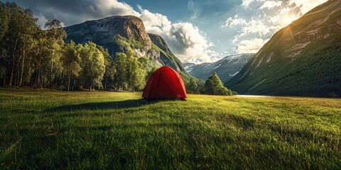 A red tent is set up in a grassy field with mountains in the background
