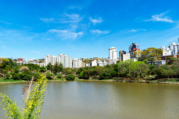 Obraz premium Residential buildings on the edge of a lake with many trees. Blue sky with clouds. City of Belo Horizonte. Brazil