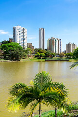 Fototapeta na wymiar Residential buildings on the edge of a lake with many trees. Blue sky with clouds. City of Belo Horizonte. Brazil