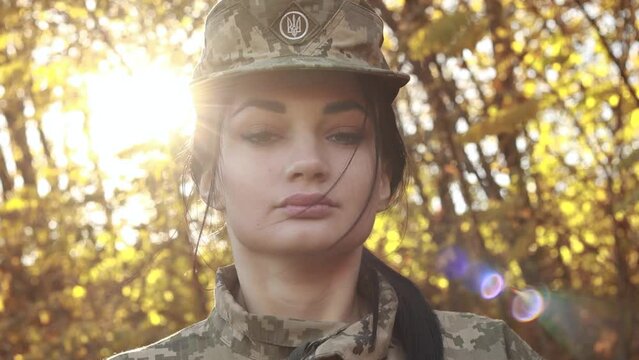 Close up camo cap national coat of arms, female servicewoman soldier dressed in the camouflage military uniform, symbol of independence. Armed Forces of Ukraine. Woman serving in ukrainian army troops