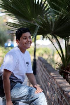 Ni&ntilde;o latinoamericano feliz recargado de una barda al aire libre