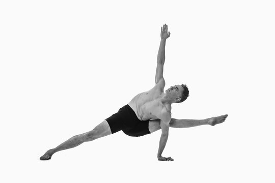 Visvamitrasana, Ashtanga yoga  Side view of man wearing sportswear doing Yoga exercise against white background. Black and white image.