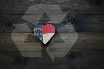 Fototapeta na wymiar wooden heart with national flag of north carolina state near reduce, reuse and recycle sing on the wooden background. concept