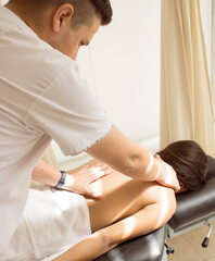 An osteopath performing back pain treatment on a female patient who is on a rehabilitation table.