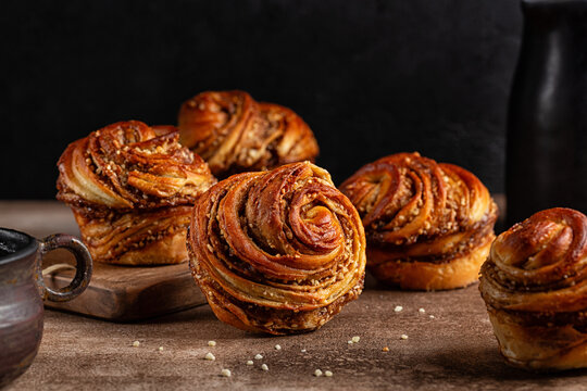 Homemade cruffins, a hybrid of a croissant and a muffin, filled with mix of butter, brown sugar and nuts. Baked in a muffin mould. Dark background.