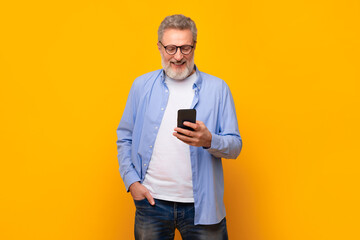 European senior man scrolling through messages on cellphone, studio
