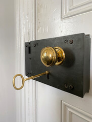 Ancient door lock with old metal key in the keyhole. Golden door handle.