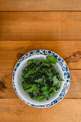 white bowl with kale leaves over blue flower plate on wood board table 